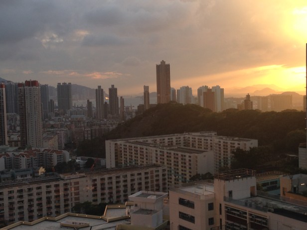 Por do sol entre montanhas e mar (o mar está entre os prédios, no centro da foto)